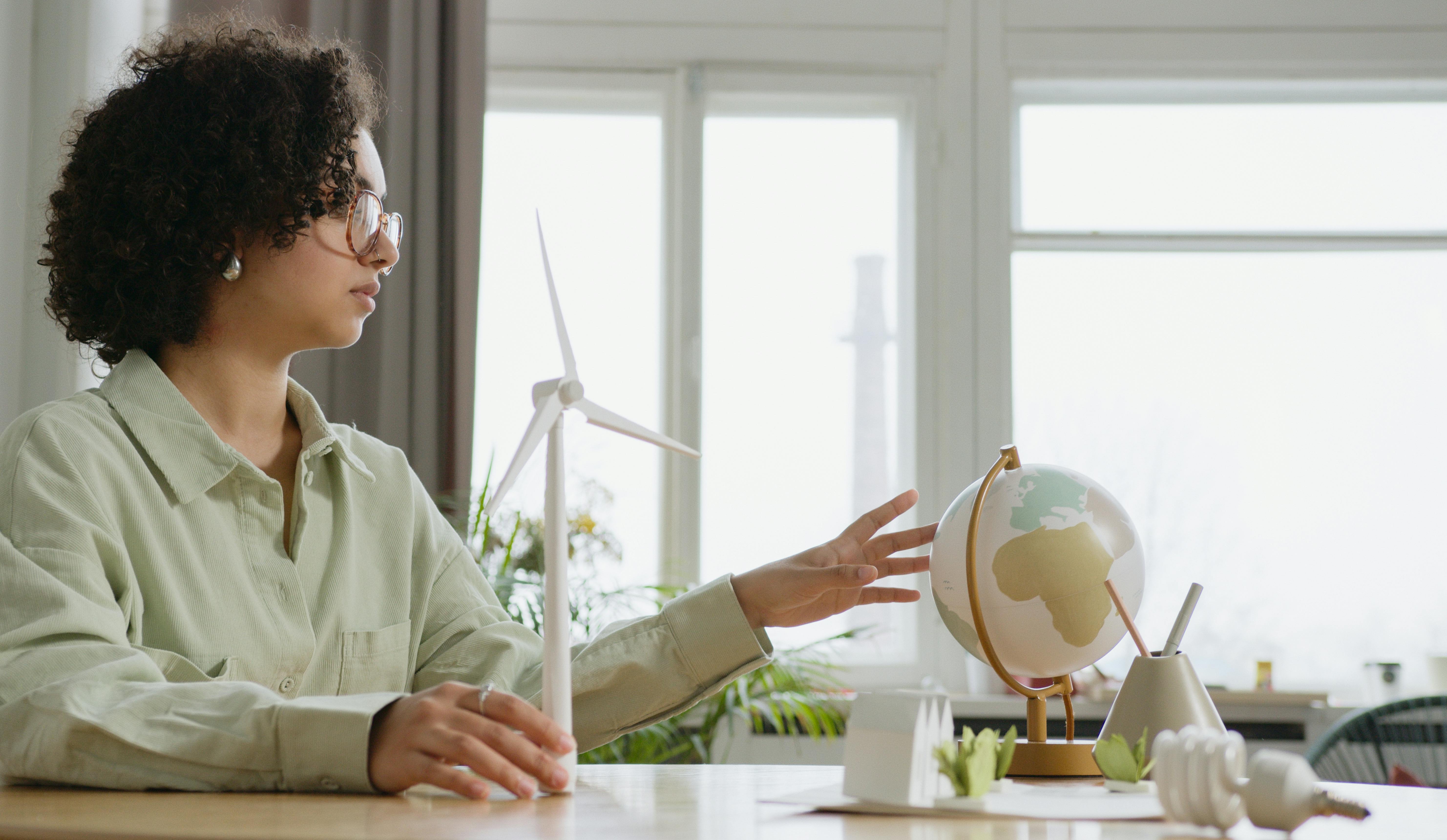 Person teaching with globe and wind turbine model